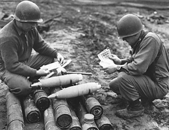 U.S. soldiers examine Safe Conduct Passes as they are loaded into 105mm Propaganda Shells for artillery dissemination